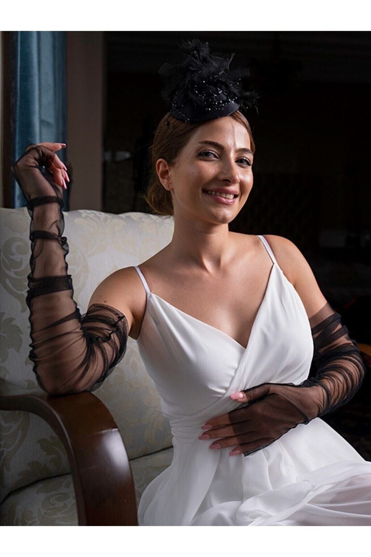 Aec Prive siyah tül eldiven ile zarif bir gelinlik giyen kadın, oturmuş poz veriyor.
