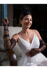 Aec Prive siyah tül eldiven ile zarif bir gelinlik giyen kadın, oturmuş poz veriyor.