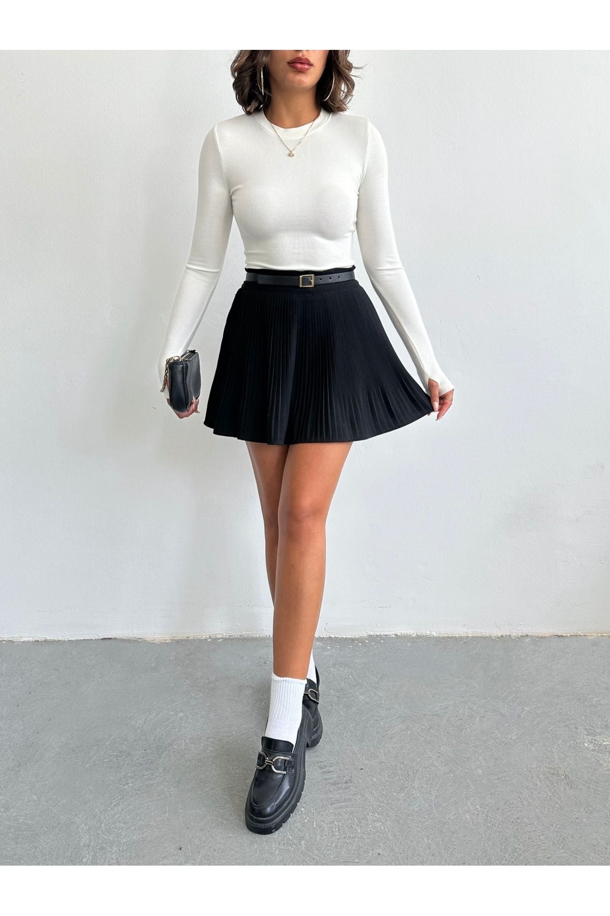 Aec Prive bambu parmak geçirmeli bluz, beyaz renkli, uzun kollu ve şık bir kombin, siyah pileli etek ile tamamlanmış