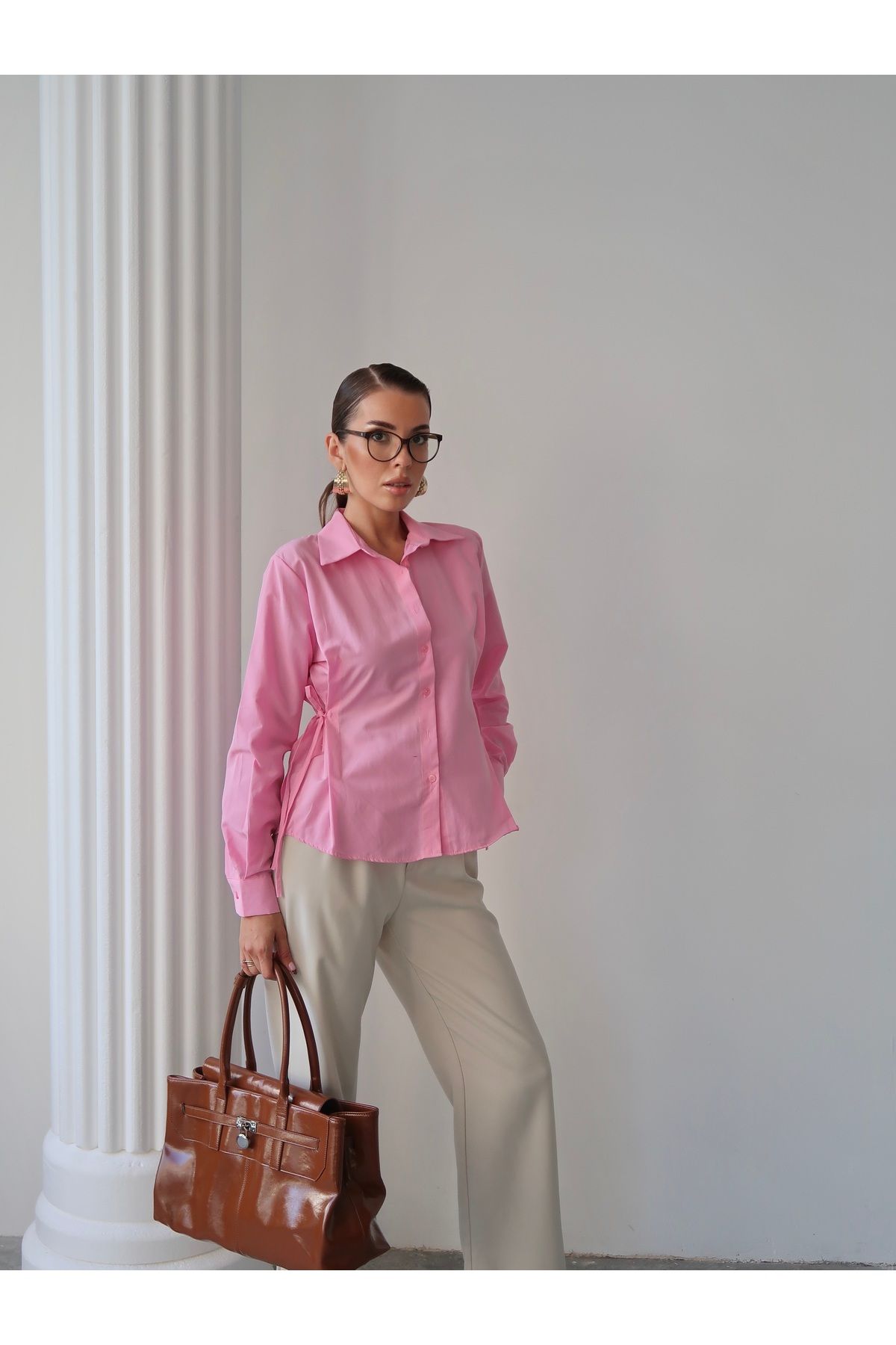 Aec Prive kadın trend gömlek ile şık kombin yapmış model, bej pantolon ve kahverengi çanta ile poz veriyor