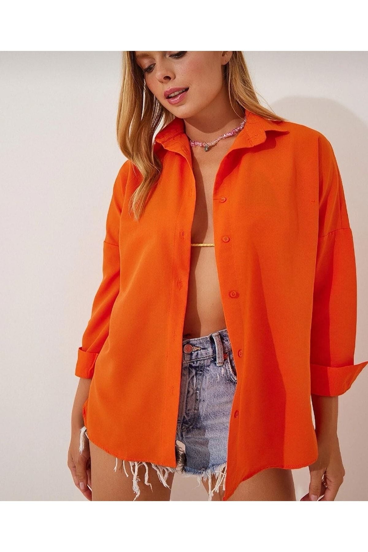 Kadın turuncu oversize gömlek, yaz modasına uygun rahat bir görünüm sunuyor.