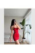 Kırmızı saten elbise ile şık bir görünüm sergileyen model, modern bir iç mekanda poz veriyor