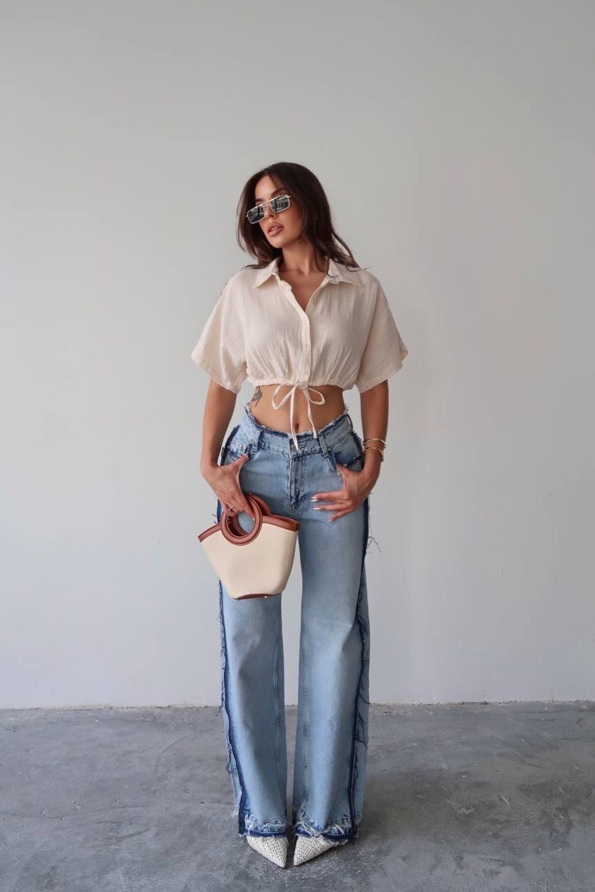 Özel tasarım kadın bağlamalı gömlek ile kombinlenmiş yüksek bel hafif mavi kot pantolon ve şık çanta