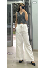 Beyaz pamuklu müslin palazzo pantolon ile kombinlenmiş gri yelekli kadın modeli